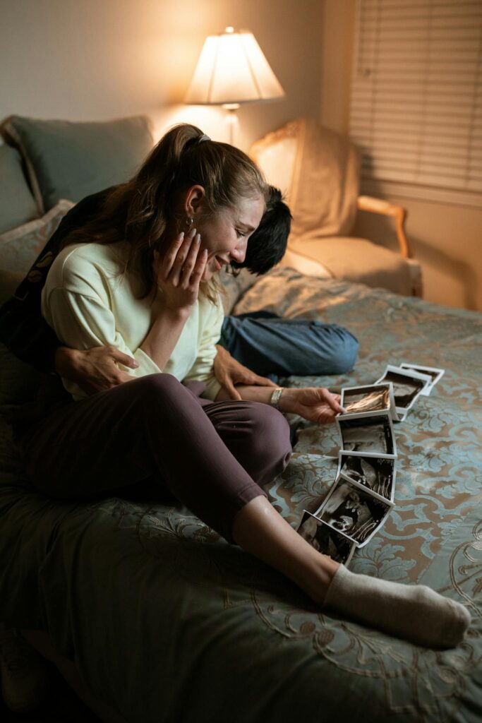 Woman in White Shirt and Black Pants Sitting on Bed